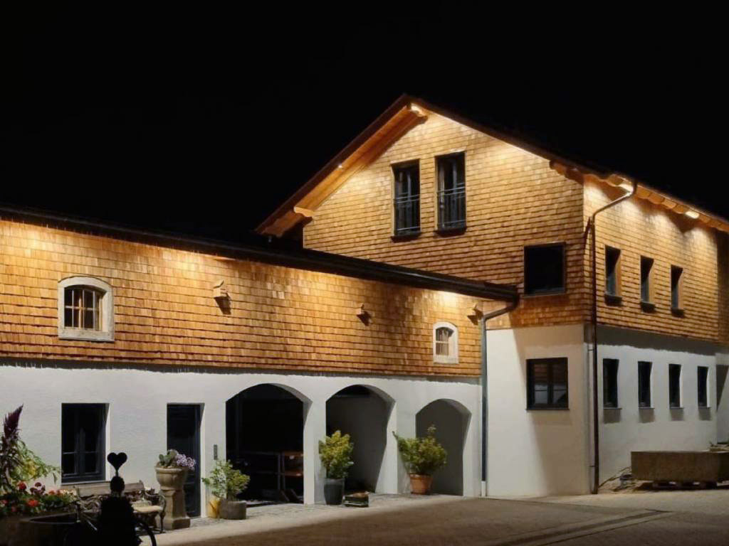 Kundenprojekt mit Holzschindel-Fassade an einem Gebäude bei Nacht
